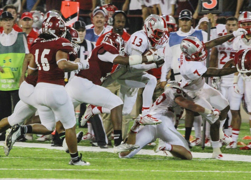 UNM quarterback Lamar Jordan (13) drives through the Aggies’ defensive line leading to a UNM fourth-quarter comeback, the first of Jordan’s career, during the Rio Grande Rivalry game against NMSU Saturday night at Aggie Memorial Stadium in Las Cruces. 