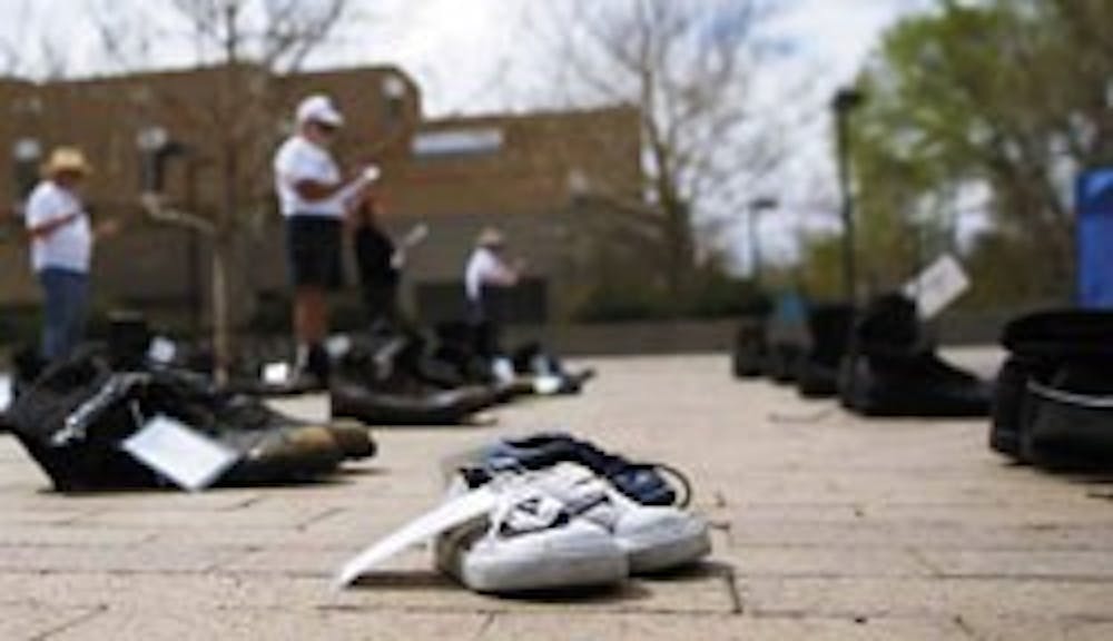 A pair of children's shoes sits among 400 pairs of boots in Smith Plaza on Monday. The traveling "Eyes Wide Open" exhibit displays boots and shoes to represent National Guard members and civilians who have died in the Iraq war.  