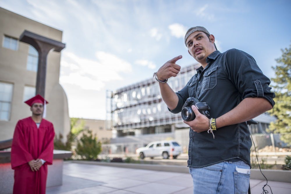 Ryan Montano directs an upcoming UNM graduate where they should look while he takes their photo on Wednesday, April 26, 2017 near Hodgin Hall. The UNM Alumni Association is hosting a free graduation photo&nbsp;shoot for upcoming graduates.
