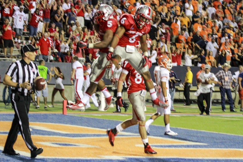 	Senior running back Kasey Carrier celebrates with sophomore tailback Jhurell Pressley after scoring one of his four touchdowns on the night. The Lobos won 42-35 in overtime in El Paso, Texas at the Sun Bowl. 