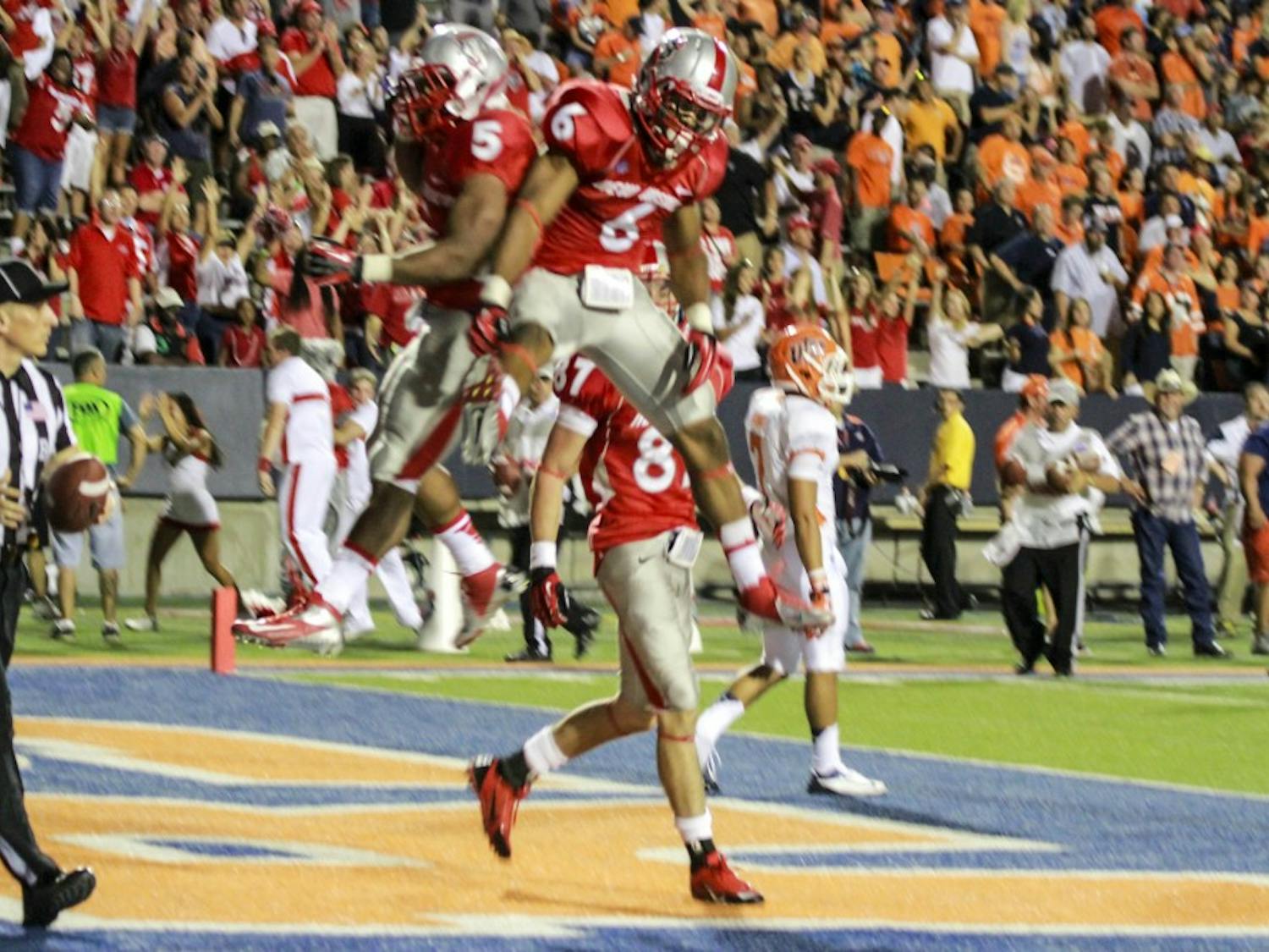 	Senior running back Kasey Carrier celebrates with sophomore tailback Jhurell Pressley after scoring one of his four touchdowns on the night. The Lobos won 42-35 in overtime in El Paso, Texas at the Sun Bowl. 