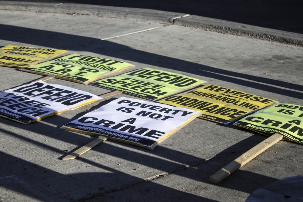 Protest signs lay on the sidewalk before a protest against the panhandling ordinance on Jan. 24, 2018.
