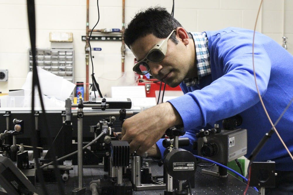 Saeid Rostami, graduate student in Optical Science and Engineering, works with a system of laser beams in the Physics Lab on Friday afternoon. Rostami is one of the students working with physics and astronomy professor Mansoor Sheik-Bahae to develop a new method of optical refrigeration to cool solids at extreme low temperatures. 