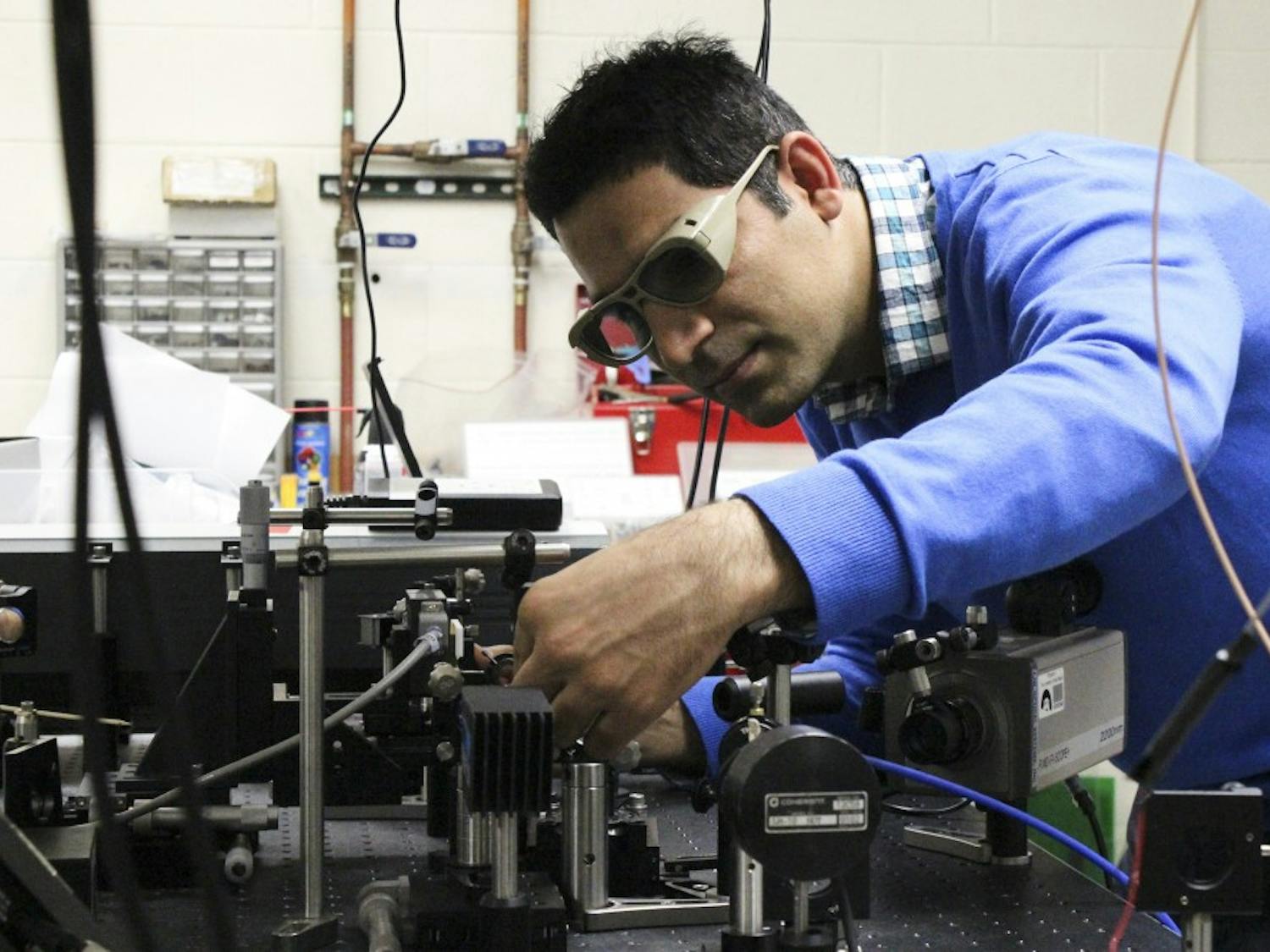 Saeid Rostami, graduate student in Optical Science and Engineering, works with a system of laser beams in the Physics Lab on Friday afternoon. Rostami is one of the students working with physics and astronomy professor Mansoor Sheik-Bahae to develop a new method of optical refrigeration to cool solids at extreme low temperatures. 