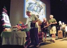UNM media arts professor Susan Dever, left, leaves a flower at an altar honoring late sculptor Luis Jim