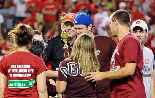 New Mexico State University fraternity and sorority members accept a trophy for collecting 13,979 pounds of canned goods. They competed with UNM's Greek organizations for the three-week period before the football game Saturday.  