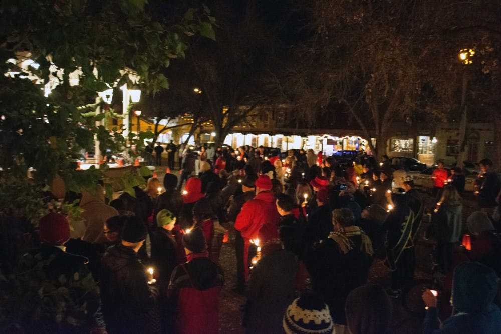 People hold lit candles at the&nbsp;UNM Truman Health Services World AIDS Day Candlelight Vigil on Tuesday night. The event aimed to raise awareness of AIDS and to commemorate those lost to the disease.&nbsp;