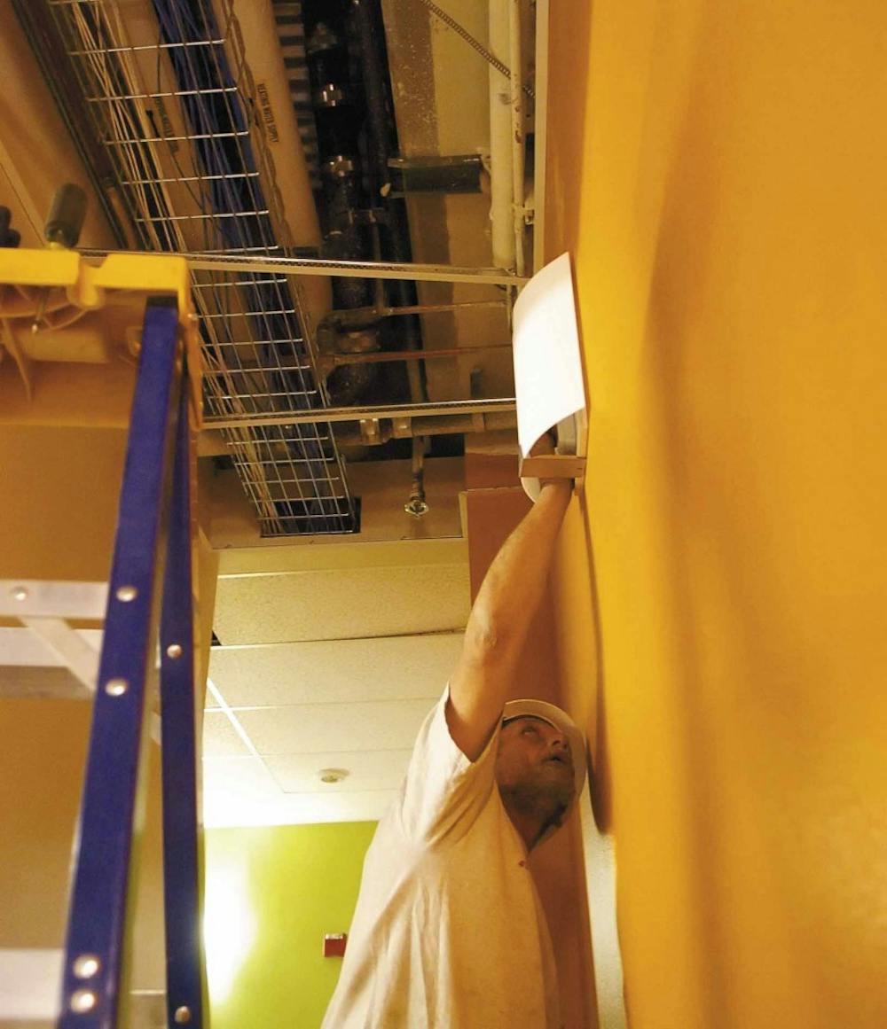 Electrician Geno Brown installs a wall sconce in the Communication and Journalism Building on Wednesday. The building's renovation is scheduled for completion around mid-May.