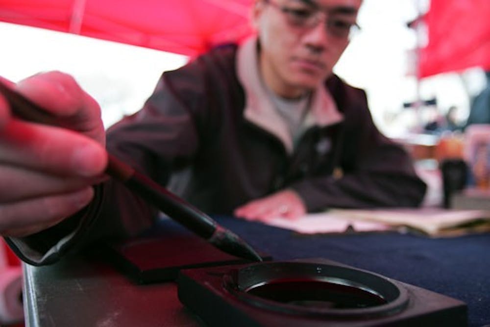 Ping-Show Wong practices calligraphy during the International Festival and Study Abroad Fair at Cornell Mall on Thursday. About 20 booths represented dozens of countries, including Turkey, India and Russia.