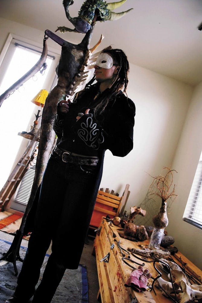 Artist Michele Basta wears a mask and costume while standing in front of one of her unfinished sculptures in her Old Town loft on Tuesday. Some of the costumes Basta makes are used in performances.