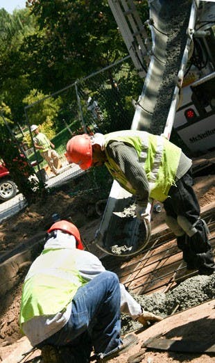 Mike Sanchez, left, and Jose Saiz lay foundation Tuesday in Smith Plaza. Construction of water lines on campus has been delayed. 