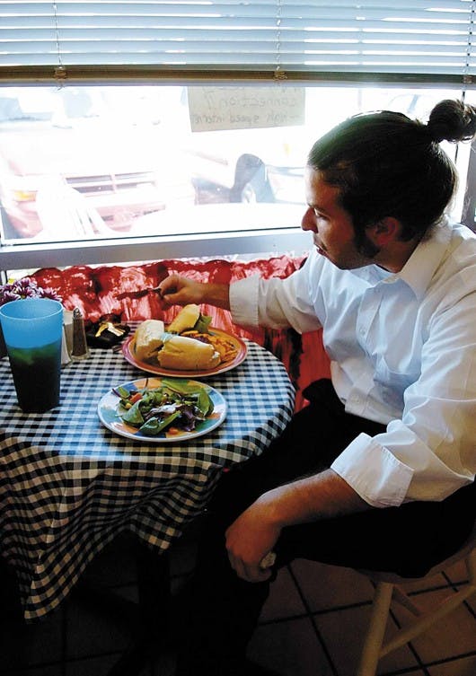 UNM alumnus Joel Rogers eats a Dijon chicken sandwich Monday at Le French Corner on San Mateo Boulevard. 