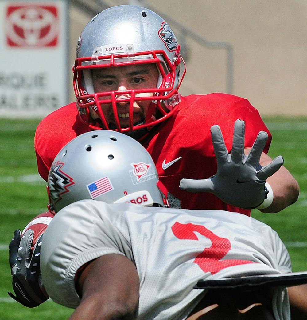 	Wide receiver Chris Hernandez, cherry, sti arms cornerback Emmanuel McPhearson, silver, during UNM’s Cherry-Silver scrimmage at University Stadium Saturday. Cherry defeated Silver 21-7.