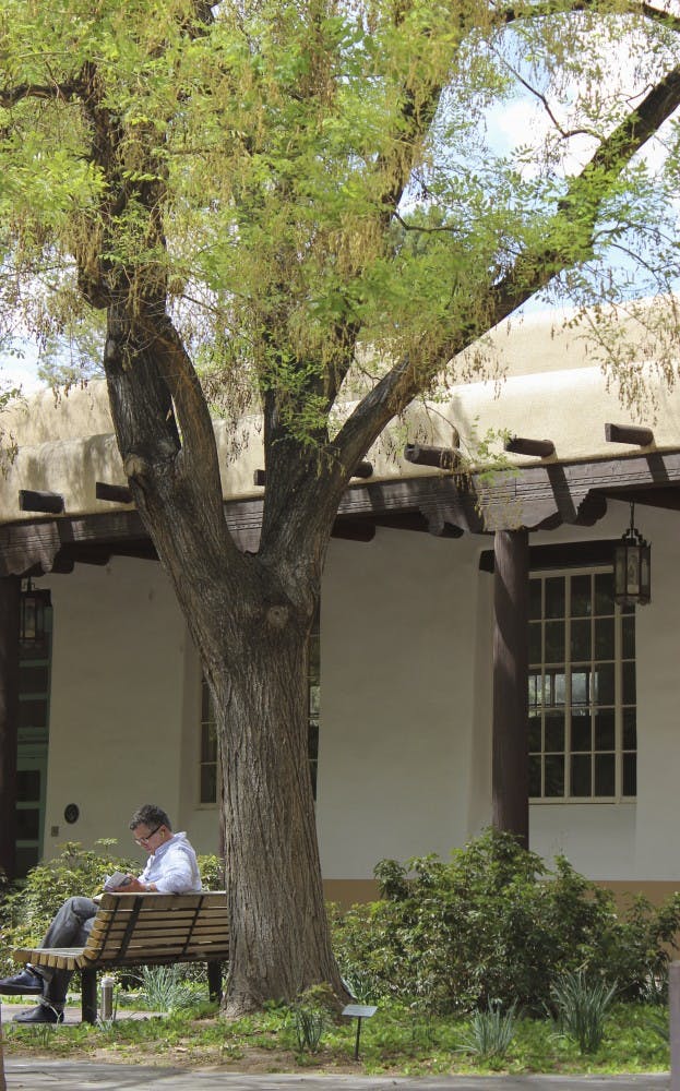 Adrian Johnston, a philosophy faculty member, reads a book beneath a Japanese pagoda on Tuesday afternoon. The Japanese Pagoda is only one of the thousands of trees that are a part of UNMs Arboretum. 
