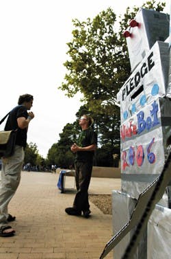 Nate Campbell, left, and New Mexico Public Interest Research Group member Vincent Richards talk Wednesday at a NMPIRG table setup in Smith Plaza to encourage students to register and pledge to vote on Nov. 7. The group constructed a robot named VoteBot 20