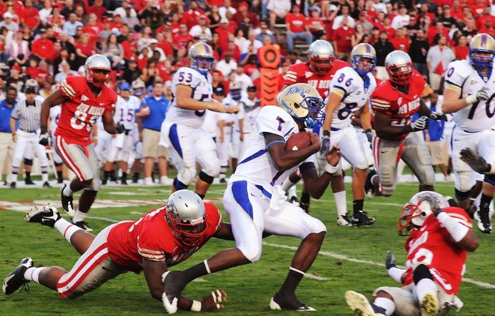 	Tulsa quarterback Shavodrick Beaver eludes UNM defenders Kendall Briscoe, left, and cornerback DeShawn Mills in Tulsa’s 44-10 stomping of the Lobos on Saturday at University Stadium.