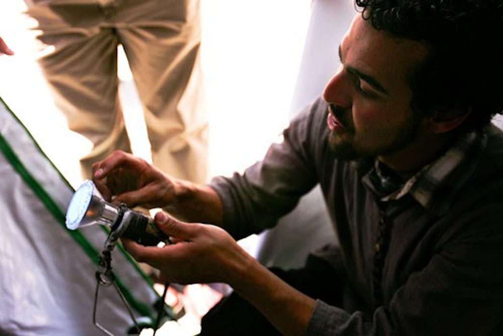 Jesse Black-Garcia of Sustainable Solutions, a retailer specializing in LED lighting, shows a customer an energy efficient grow light during the UNM Growers' Market and Sustainability Fair in Cornell Plaza on Thursday. 