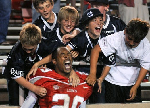 Lobo safety Blake Ligon celebrates Saturday's 36-28 win against Arizona with members of the La Cueva Bears YAFL team at University Stadium.  