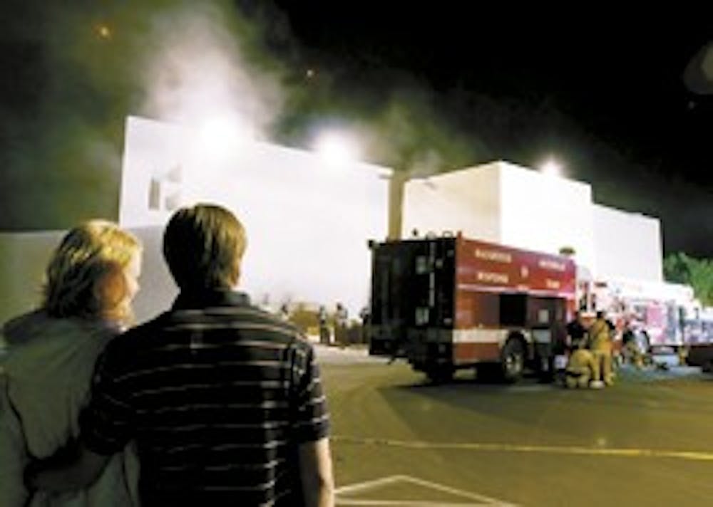 UNM students Erin Husher, left, and Evan Kias watch firefighters and other emergency personnel react to the fire that started in Zimmerman Library late Sunday night.