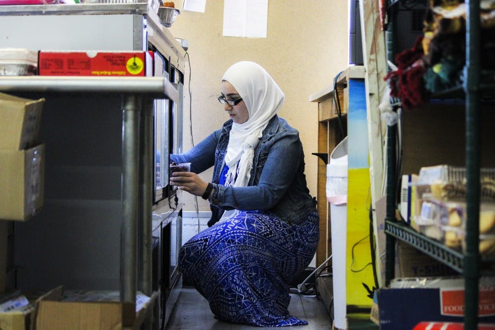 Deena Aggad pulls out fresh olives for a customer Wednesday afternoon at her family's market Cafe Istanbul. The Aggads are a Palestinian-Muslim family, one of many in the community attempting to acclimate to the current political climate.