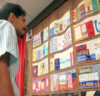   UNM employee Ron Estrada looks at a quilt depicting Zimmerman Library's history at a commemoration Wednesday. 