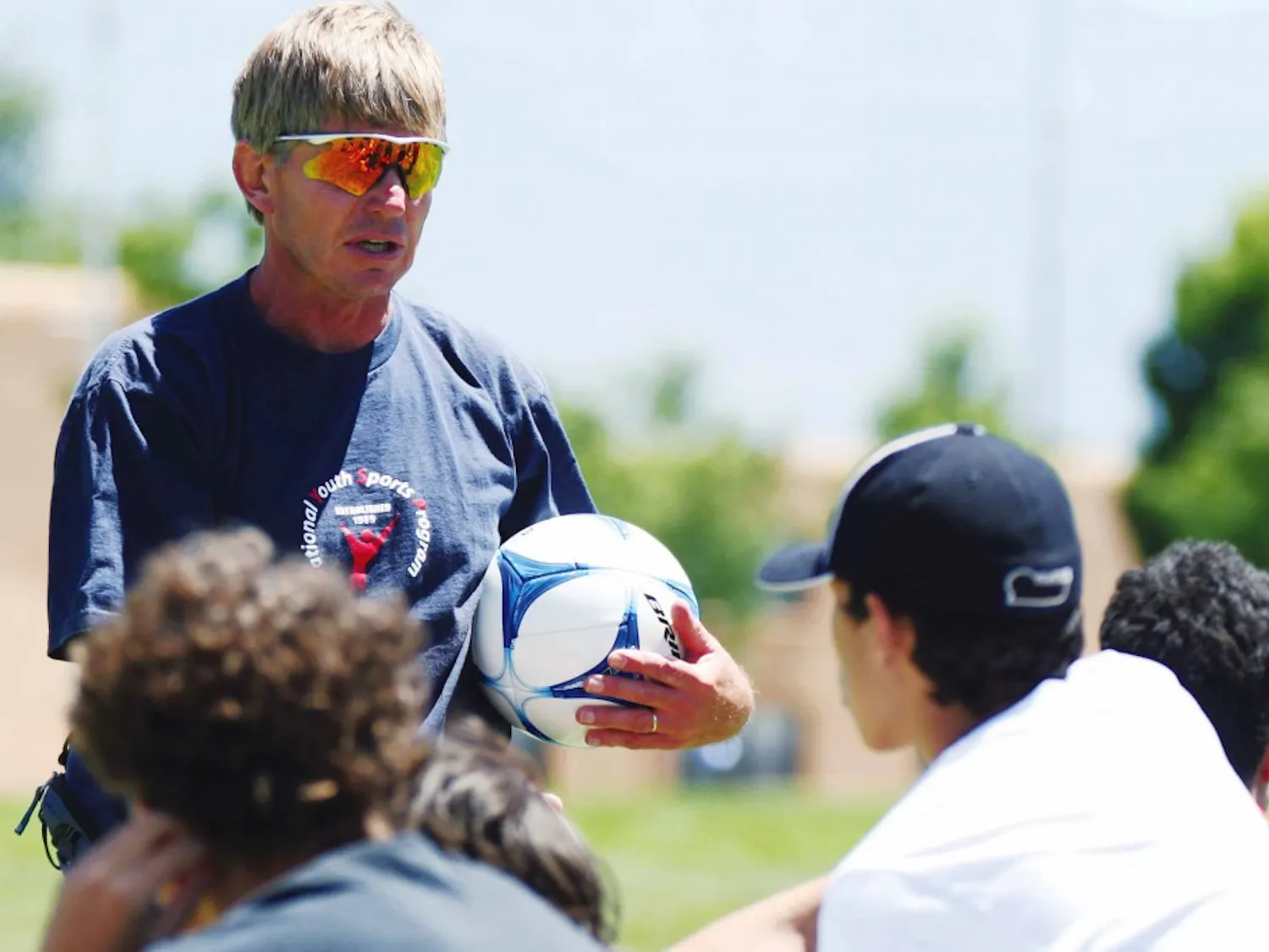 Coach Andy Murray talks to youth soccer players before doing drills June 8 on Johnson Field. They are participating in the National Youth Sports Program, which has been running for the past 36 years.