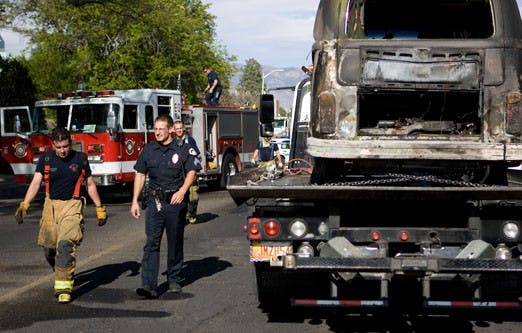 Albuquerque firefighter Jose Gomez, left, and UNM Police Sgt. Peter Rogahn walk past a vehicle that caught fire Tuesday at the corner of Las Lomas Road and Yale Boulevard. The incident is still under investigation, police said. 