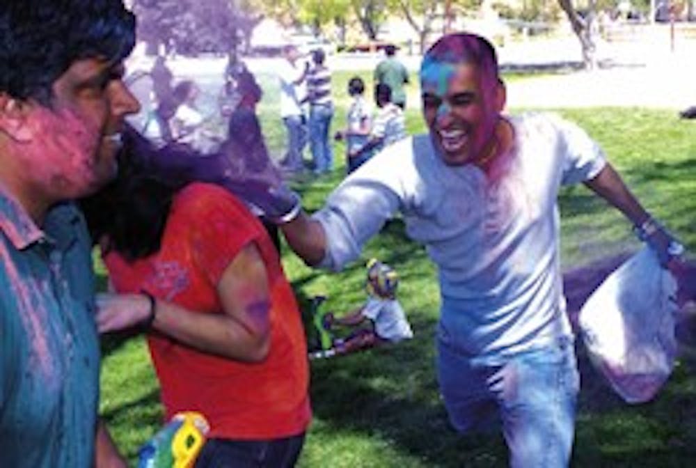 Japji Hundal, right, covers Bitu Sheth with powdered colors during the Holi festival at Johnson Field on Sunday.