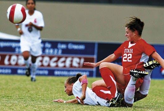Midfielder Kaela Kelly is squashed by Carisse Winegar during the Lobos' 3-0 loss to Utah at the UNM Soccer Complex on Sunday.