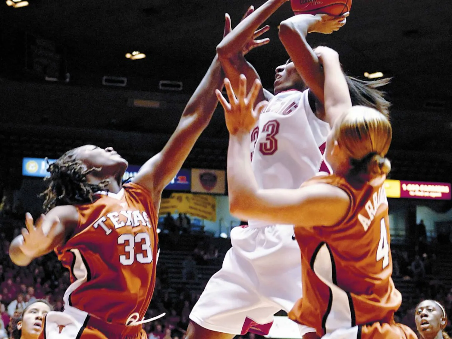 Lobo forward Dionne Marsh is fouled by Texas' Tiffany Jackson, left, and Erika Arriaran in the second half of the Lobos' 63-60 win at The Pit on Friday.