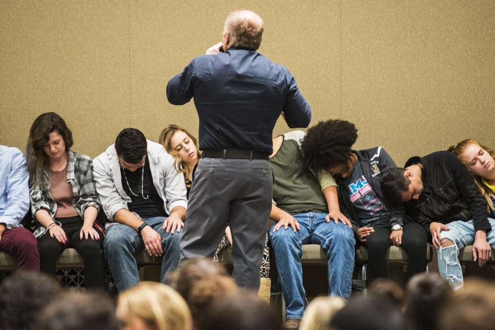 Rich Guzzi stands center stage while attempting to hypnotize a group of students in the SUB Ballroom Monday, Oct. 24, 2016. Guzzi played a rotating music track while speaking to the students, then, once they were&nbsp;hypnotized, proceeded to hold a comedy performance involving them.&nbsp;