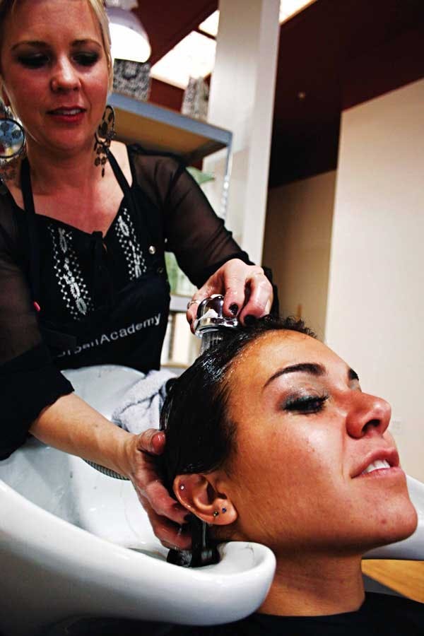 Stylist Paige Davis washes Amanda Schofield's hair Wednesday at Urban Academy. On Monday, customers can get a free shampoo, cut and style if they bring in five nonperishable foods. 