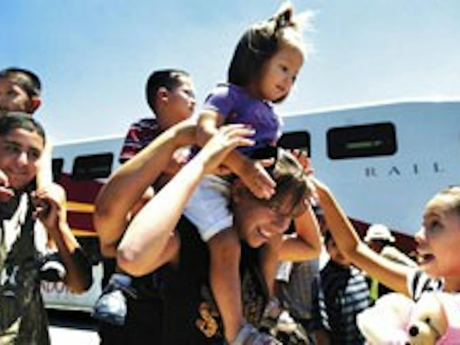 Angelina Abeyta, right, helps her 2-year-old cousin, Kathleen Abeyta, onto Alexis Abeyta's shoulders after the family rode the Rail Runner Express from Bernalillo to Alvarado Station in Downtown on Wednesday.