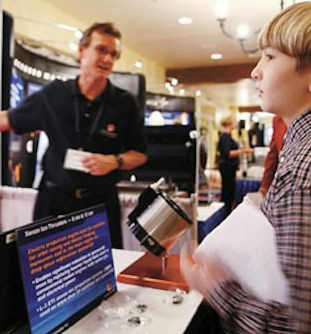 Ray Robinson, left, of L3 Electronic Technologies, explains how his company's components are used on commercial and NASA satellites to sixth-grader Seth Taylor at the Space Technology and Applications International Forum on Monday at the Hotel Albuquerque