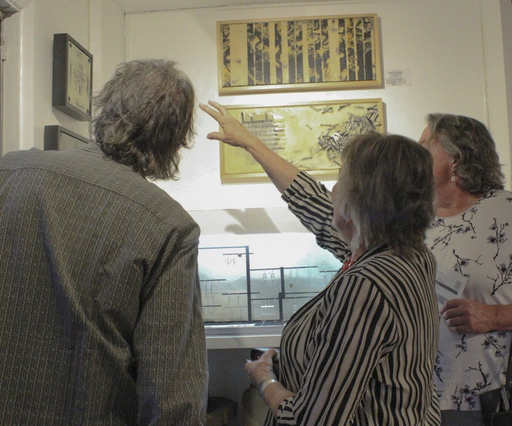 Artist Harriett Tsosie, center, talks to art goers during her exhibit Linguicide Friday evening at Weyrich Gallery. Tsosies artist talk will take place on April 25 at Weyrich Gallery. 