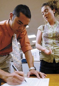 Dean Manglona signs law school student Kristin Casper's clean-energy petition to help make the University an environmentally friendly campus Monday at the UNM School of Law. 