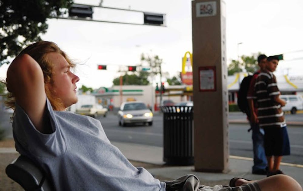 Student Evan Locke waits for a Rapid Ride Blue Line bus at the corner of Central Avenue and Yale Boulevard on July 15. The new service extends from UNM to the West Side.