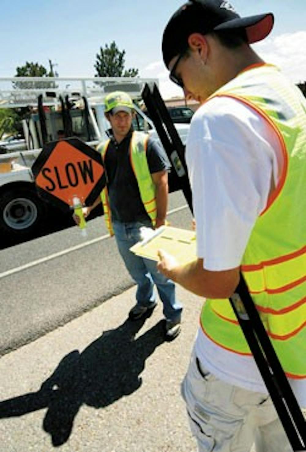 Jerod Waggerman, left, tries to slow down traffic as Justin Vollbrecht notes the road depth of a section of Paseo del Norte on Monday.