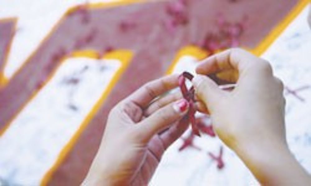 ASUNM president Brittany Jaeger puts pins through maroon ribbons in the SUB on Wednesday to support the victims of the Virginia Tech shooting that took place Monday. 