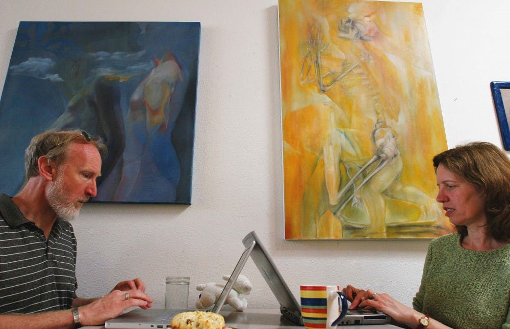 Steve Wheeler, a visiting professor at UNM, and Mimi Kusch do work at Winning Coffee Co. on Tuesday. Hanging in the cafe is artwork by artist and radio DJ BillyJoe Miller.