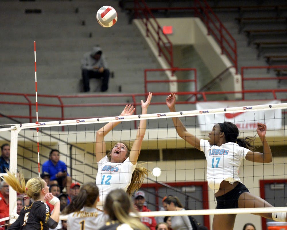 Cassie House (12) and Skye Gullatt (17) leap to knock down Wyoming's overpass at Johnson Center Thursday night. The Lobos lost to Wyoming 3-2.