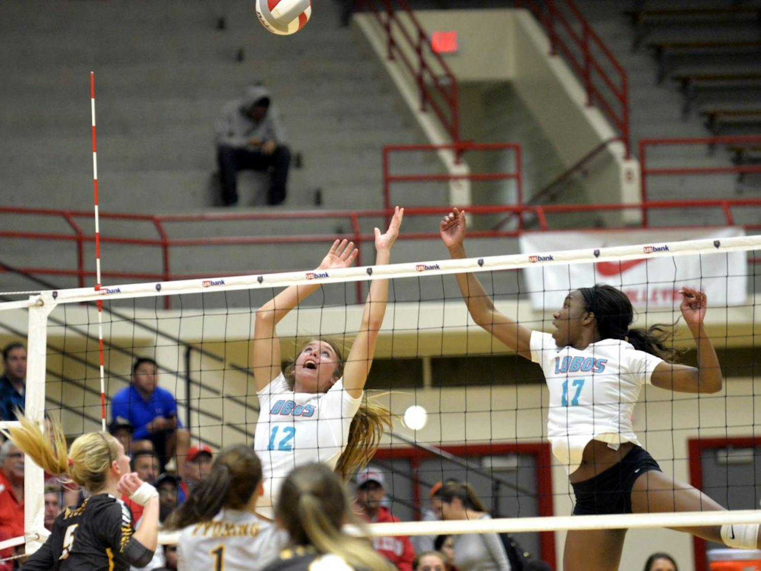 Cassie House (12) and Skye Gullatt (17) leap to knock down Wyoming's overpass at Johnson Center Thursday night. The Lobos lost to Wyoming 3-2.