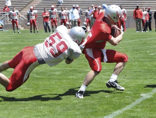 Linebacker Seth Johannemann clutches quarterback Tate Smith's jersey on Saturday at University Stadium. Smith said head coach Mike Locksley divvied the talent up equally, which was a stark contrast from former head coach Rocky Long. Long often stacked the