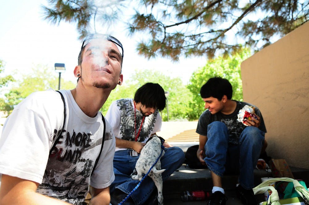 	Student Noah Storie, left, smokes Monday in a designated smoking area near Zimmerman Library. No sign is present to indicate this is a smoking area.