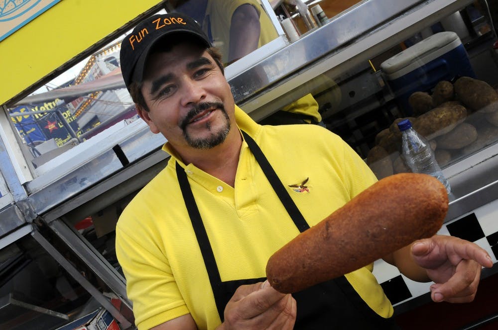 	Manuel Mendoza shows off a giant corn dog Sept. 15at the State Fair. The fair has several vendors offering a variety of foods, from turkey legs to deep-fried Twinkies.