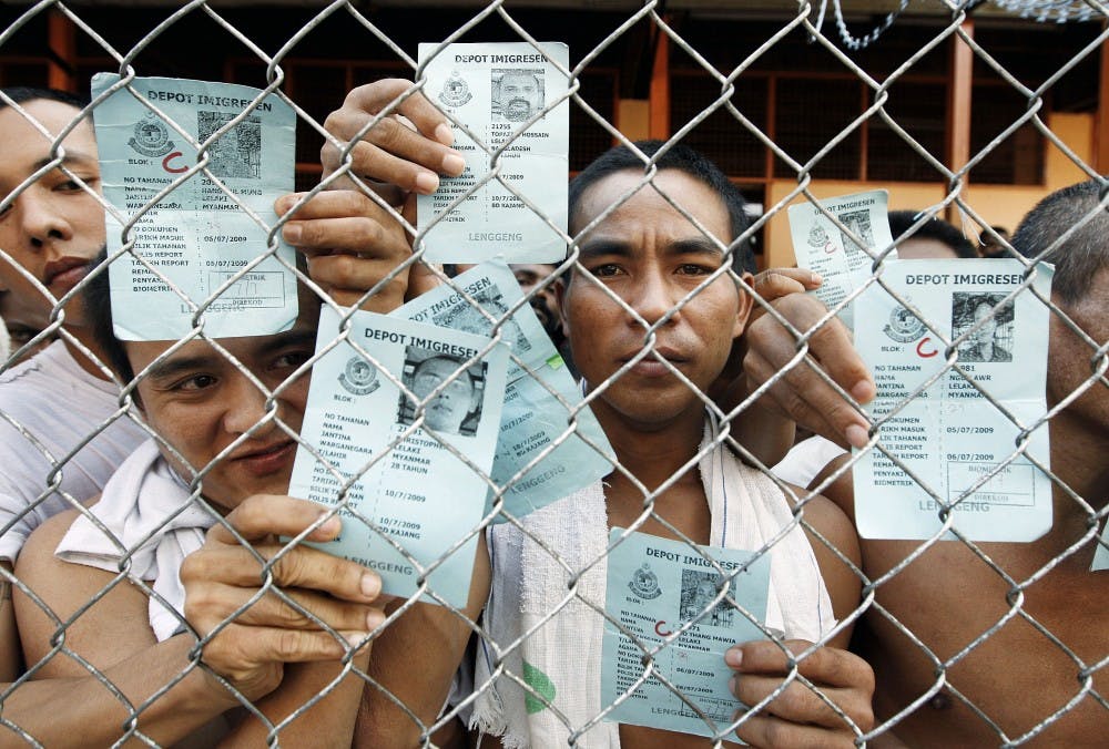 	Mynanmar detainees hold up their documents through a fence at the Lenggeng Immigration Center on the outskirts of Kuala Lumpur, Malaysia, on July 23.