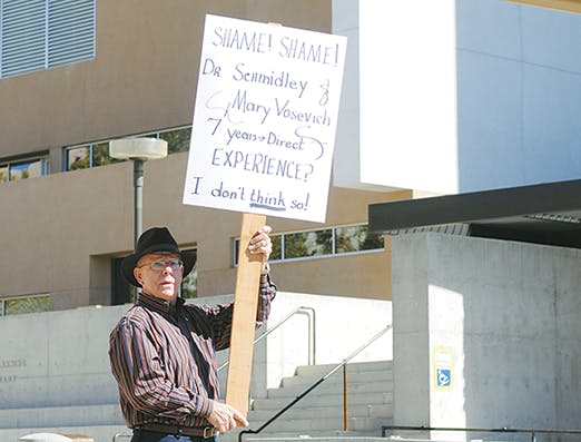 Bob Harris protests the hiring of President David Schmidly's son, Brian, on Sunday in front of the Bookstore. Brian Schmidly was hired as associate director of sustainability Wednesday but withdrew his application Sunday.
