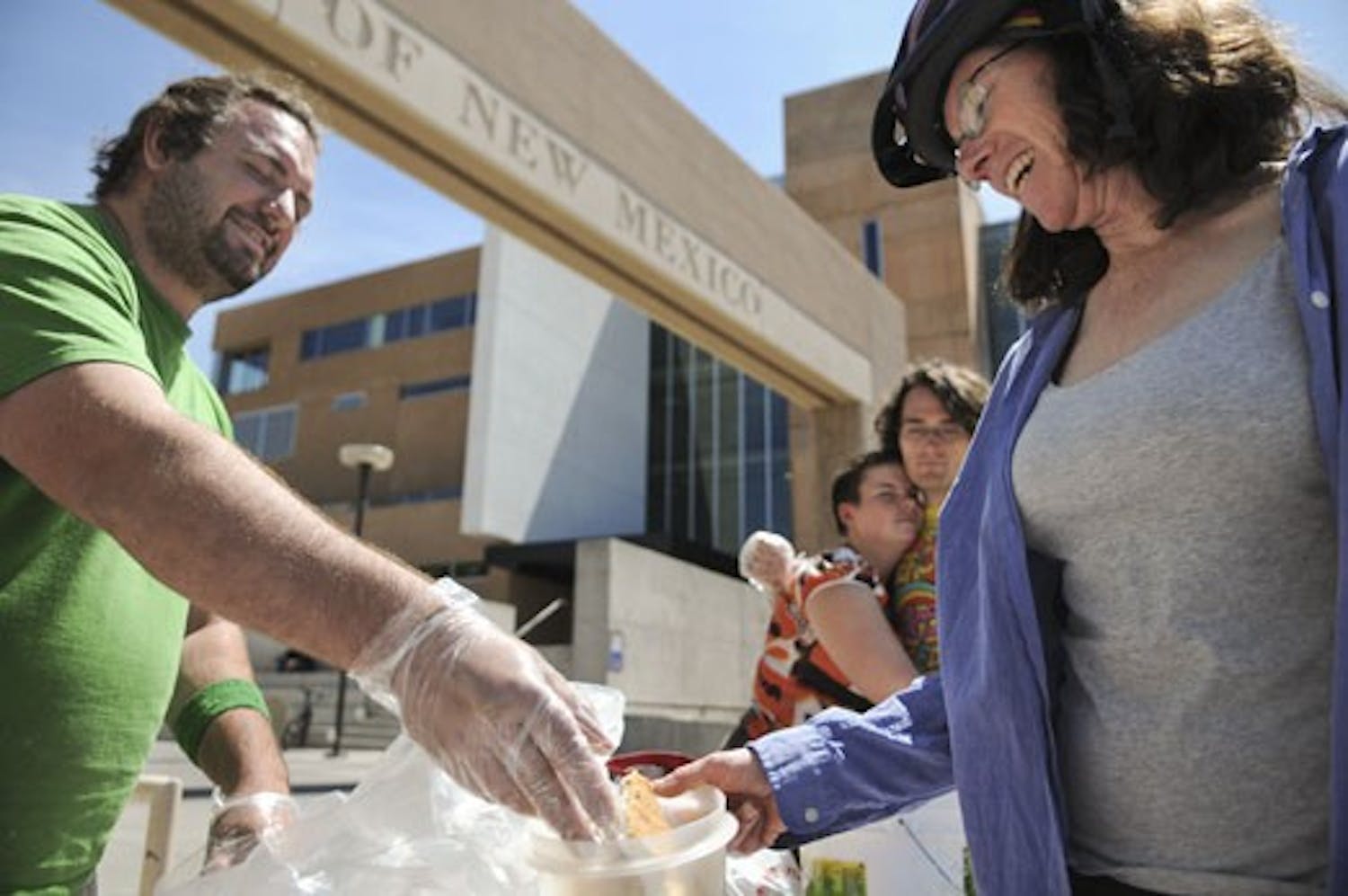 Dante John Terminello of Food Not Bombs serves Jackie Shane on Wednesday in front of the UNM Bookstore. Food Not Bombs is facing a court injunction for continuing to prepare and offer food to the public without a permit.