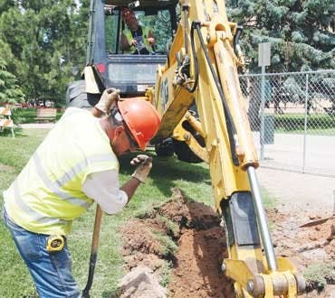 Rueben Marcias guides Jorge Aragon's backhoe during construction on the campus water system. 