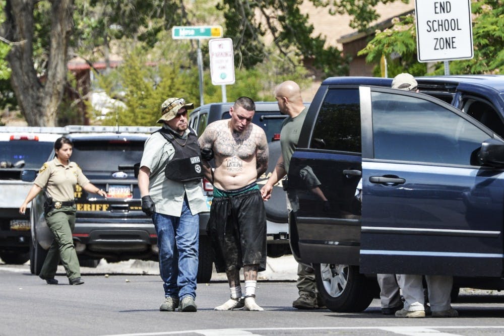 Officers escort Joseph Gutierrez into a squad car after he barricaded and surrendered himself to SWAT Monday June 27, 2016 near UNM Stadium.&nbsp;The SWAT situation lasted two hours and was due to an outstanding federal warrant that Gutierrez possessed.&nbsp;